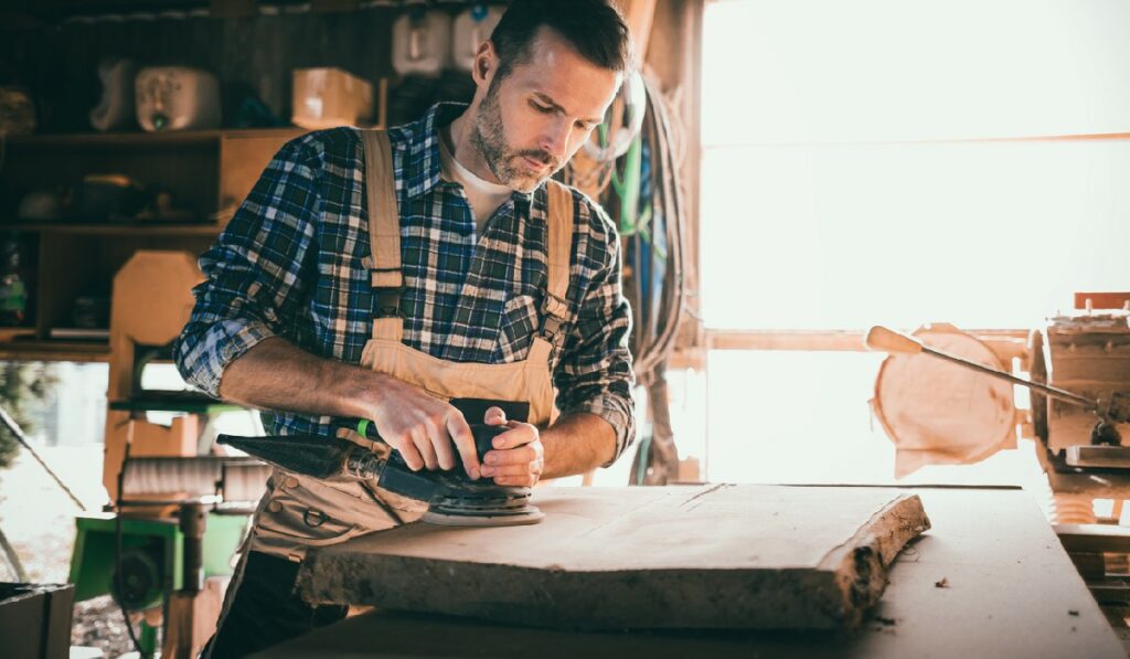 Carpenter using woodworking tools for craft work in carpentry workshop