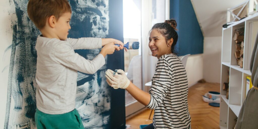 Mother and son working together on repainting a wall in their living room