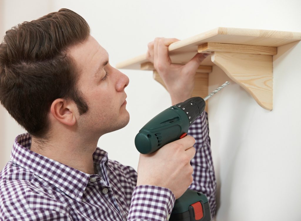 Man mounting a wall shelf